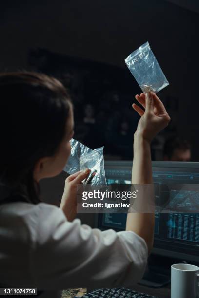 portrait of a female police officer examining evidence in a ziplock bag - future proof stock pictures, royalty-free photos & images