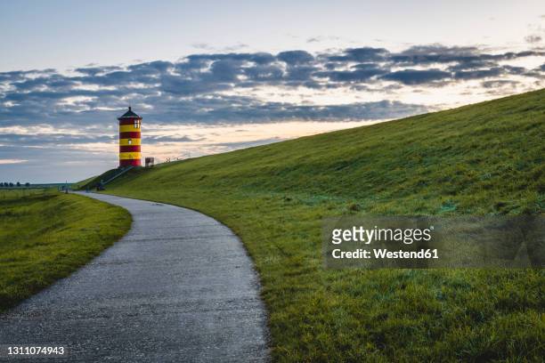 germany, lower saxony, krummhorn, footpath leading to pilsum lighthouse at dusk - lower saxony stock pictures, royalty-free photos & images