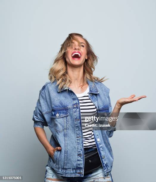 happy young woman in oversized jeans jacket - giant kick stock pictures, royalty-free photos & images