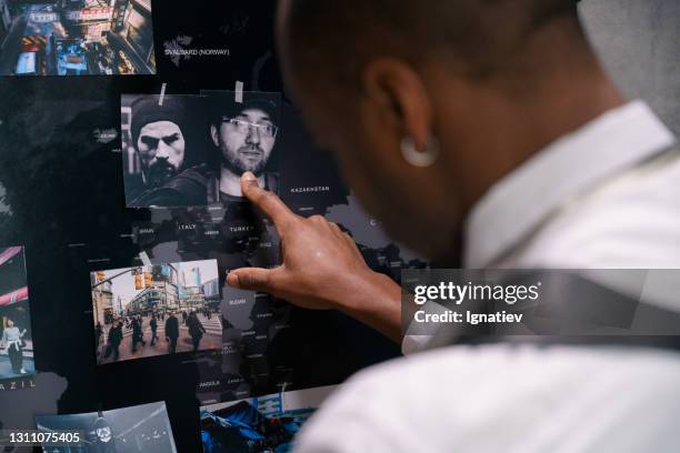 portrait of a thoughtful dark-skinned man looking at a map of the world - wanted poster stock pictures, royalty-free photos & images