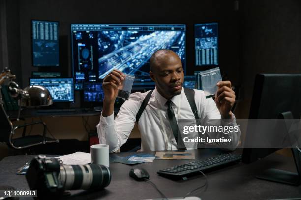 thoughtful detective examines evidence stock photo - justiça criminal imagens e fotografias de stock