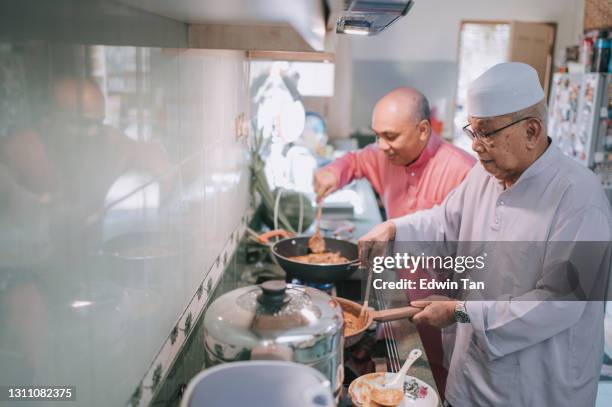 malay familie großvater und vater kochen traditionelles essen curry seite an seite in der küche vorbereitung für hari raya familientreffen abendessen - hajj stock-fotos und bilder