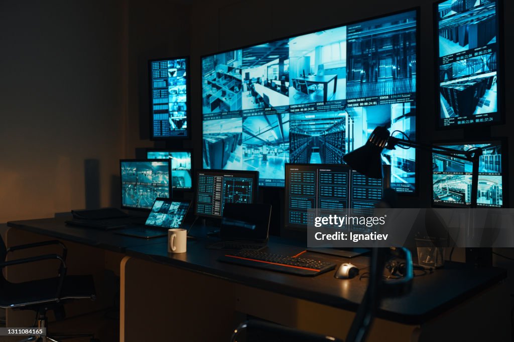 Um local de trabalho de segurança com um moderno painel de controle de alta tecnologia na forma de monitores grandes que exibem informações em tempo real de câmeras de vigilância de vídeo externas por 24 horas.