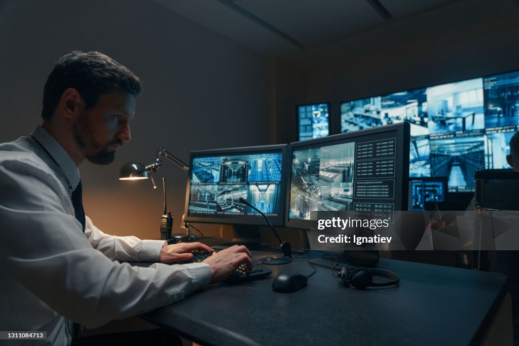 Guardas de segurança monitorando câmeras de CFTV modernas dentro de casa