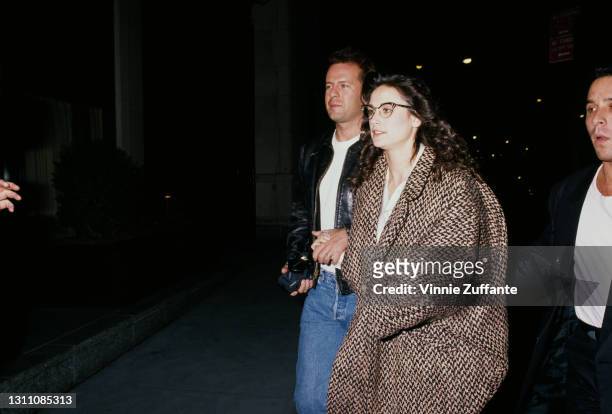 American actor Bruce Willis, wearing a black leather jacket, white t-shirt and blue jeans, and his wife, American actress Demi Moore, wearing a...