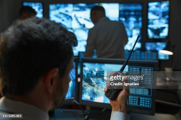 a male security guard in the security room keeps order with the help of modern technologies. the security service monitors display all the information from the surveillance cameras. - finland police stock pictures, royalty-free photos & images
