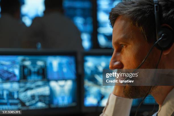 close-up van het gezicht van een mannelijke veiligheidsagent, veiligheidsdienst, politieambtenaar, reddingsdienst, die met een draadloze hoofdtelefoon onderhandelt. - security guard stockfoto's en -beelden