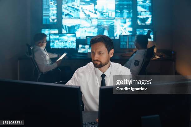 an employee of security, security, police, rescue service, fbi, cia, sits at his workplace behind monitors. - military computer stock pictures, royalty-free photos & images