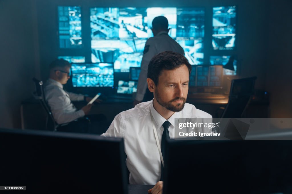 An employee of security, security, police, rescue service, FBI, CIA, sits at his workplace behind monitors.