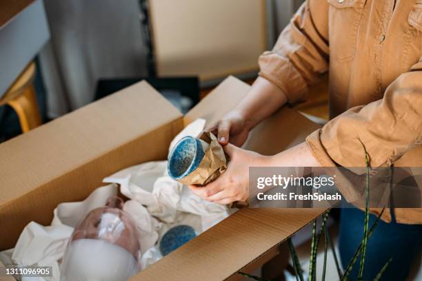 moving out- unrecognizable person packing up ceramics in paper sheets and cardboard boxes- close up shot - packing stock pictures, royalty-free photos & images