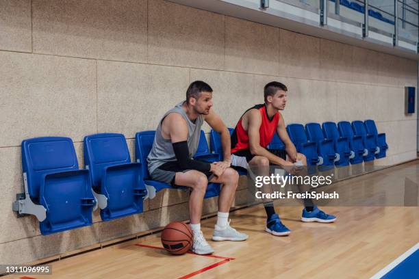 two basketball players sitting on the bench during a time out - basketball sideline stock pictures, royalty-free photos & images