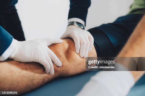 close up of patient's knee cap and doctor's hands examining the problem - meniscus stock pictures, royalty-free photos & images