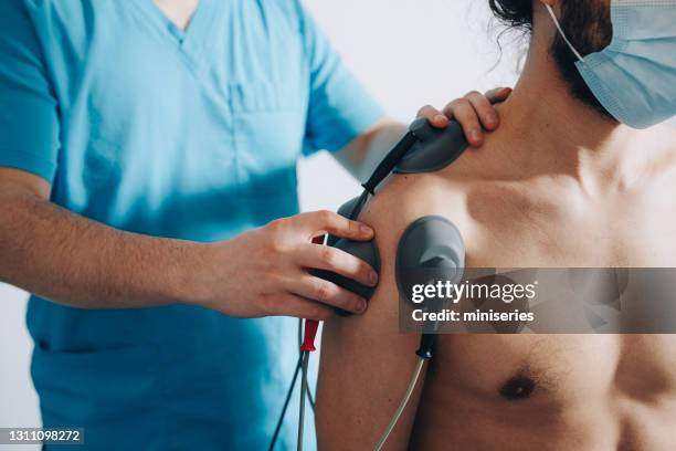 cerca de un pecho masculino con electrodos pegados al hombro del paciente - radiacion electro magnetica fotografías e imágenes de stock