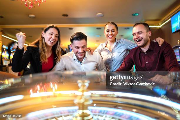 group of friends playing roulette in casino - roulette stock pictures, royalty-free photos & images