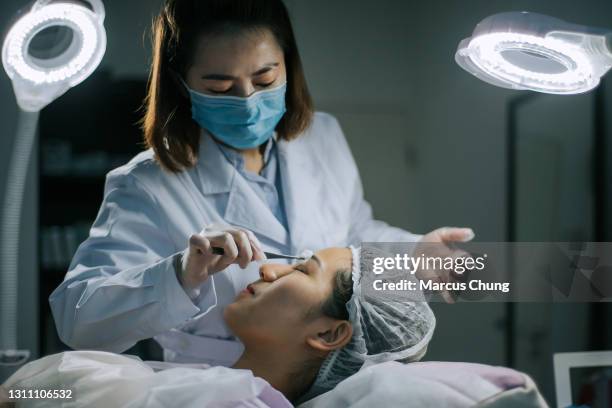 asian chinese women cosmetologist cleaning her customer face with cotton ball before the operation start in surgery room - woman applying cotton ball stock pictures, royalty-free photos & images