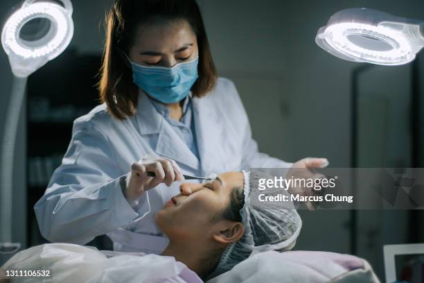 asiatiska kinesiska kvinnor kosmetolog städar sitt kundansikte med bomullsboll innan operationen börjar i operationsrummet - woman applying cotton ball bildbanksfoton och bilder