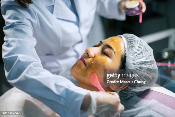 asian chinese female cosmetologist is applying moisture on patient's face for facial treatment - botulism bacterium stock pictures, royalty-free photos & images