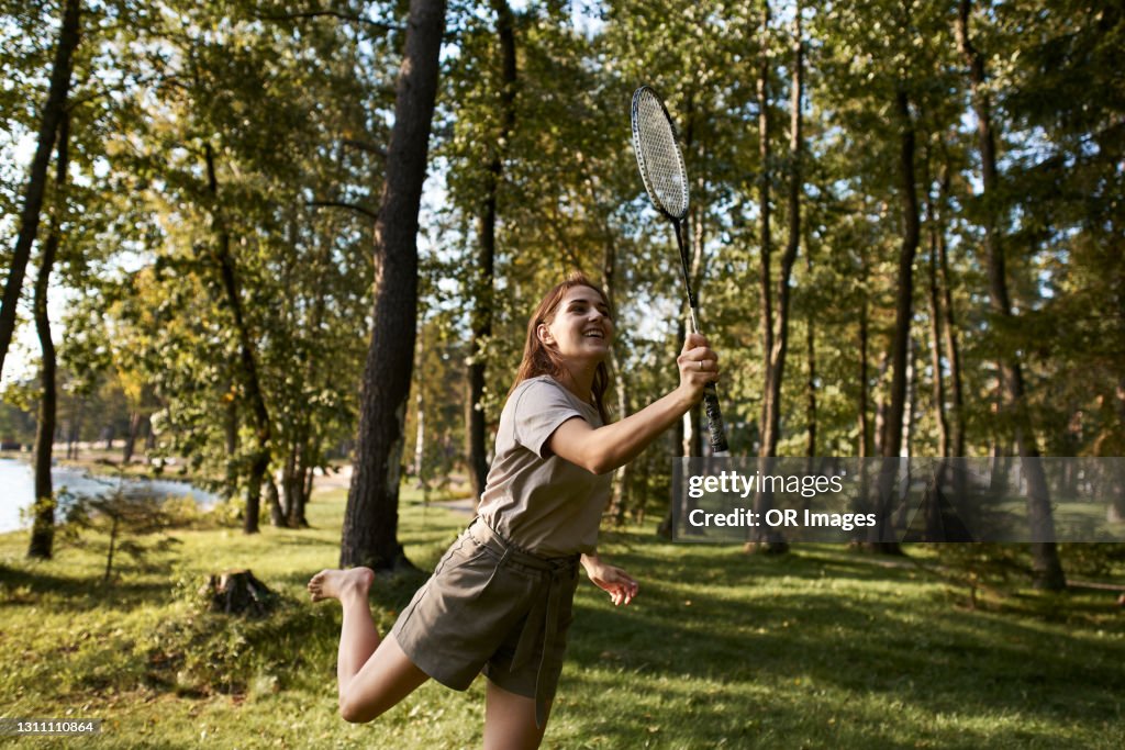 Happy young woman playing badminton at the lakeside
