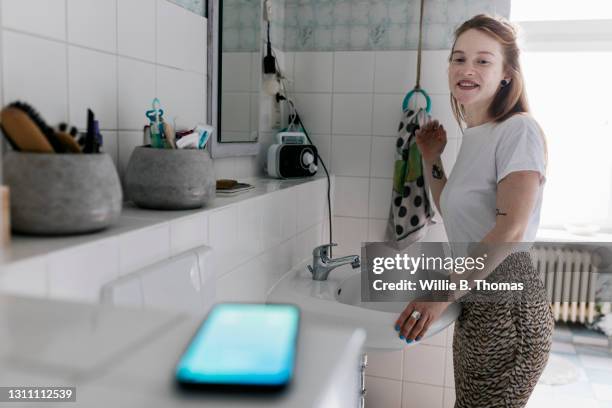 girl in bathroom at home noticing her phone going off - notificatiepictogram stockfoto's en -beelden