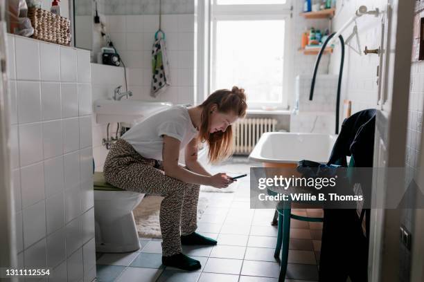 girl in bathroom at home using smartphone - woman in bathroom stock pictures, royalty-free photos & images