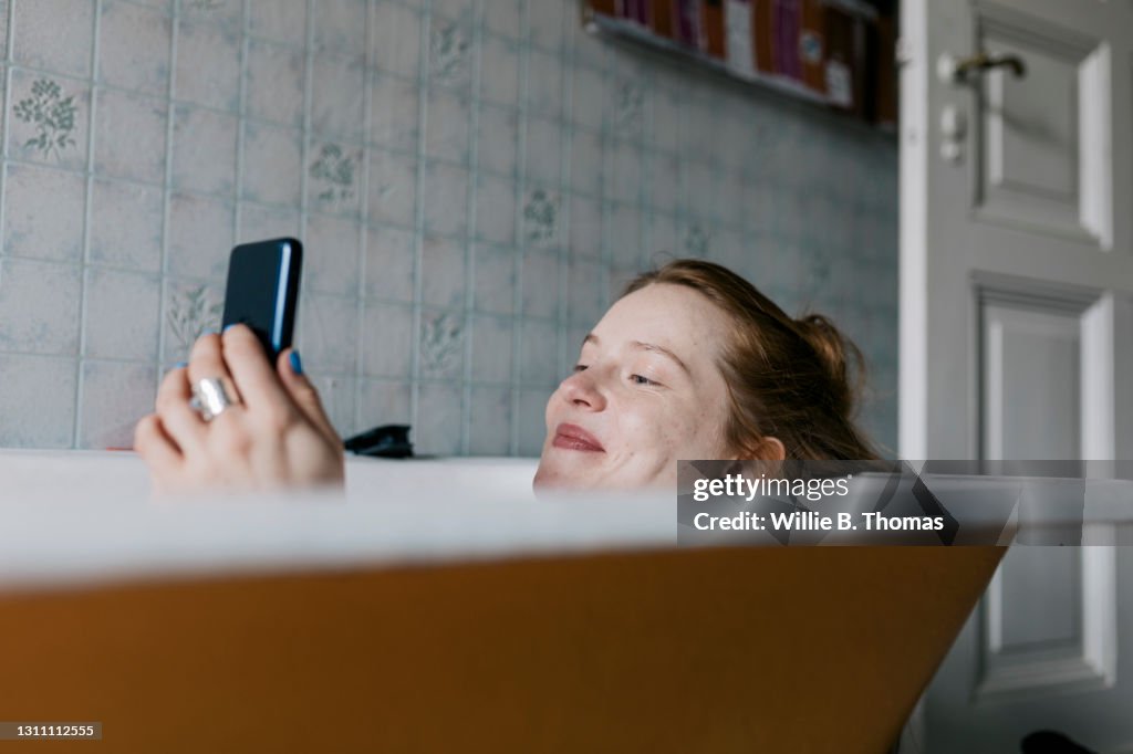 Woman Taking Bath And Smiling While Messaging Someone