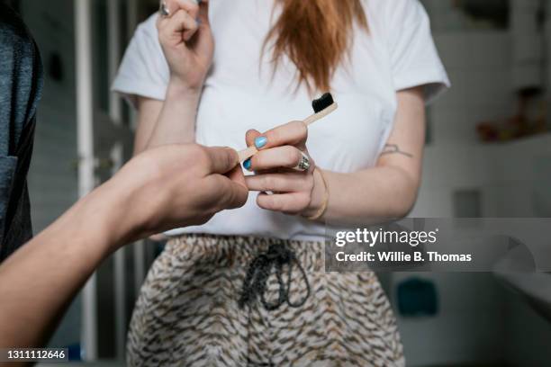 close up of woman passing man a toothbrush - passing giving photos et images de collection