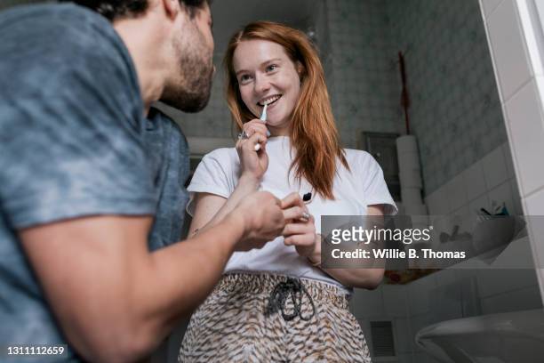 girl passing her boyfriend his toothbrush - nur erwachsene stock-fotos und bilder