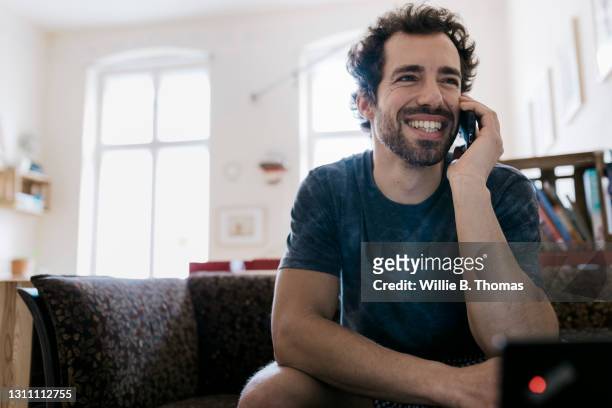 man smiling while talking on smartphone to someone - solo un uomo di età media foto e immagini stock