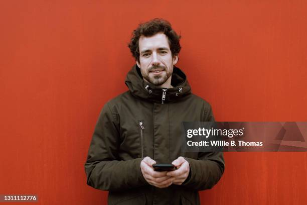 portrait of man holding smartphone - winter jacket stock pictures, royalty-free photos & images