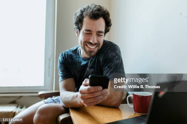man smiling while messaging woman on dating app - mid adult men stock pictures, royalty-free photos & images