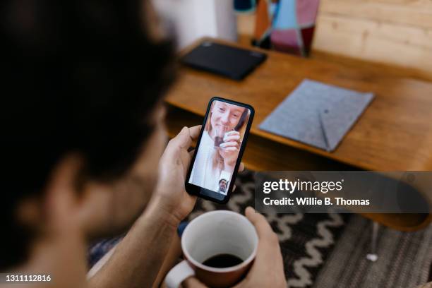 man video calling partner using smartphone - zoom date stock pictures, royalty-free photos & images