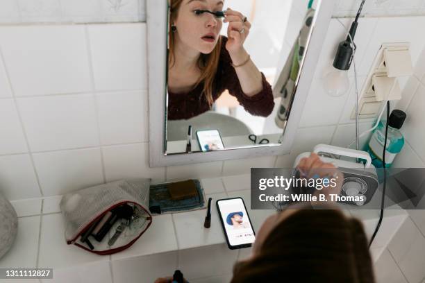 girl with read hear putting make up on in bathroom - preparation stock-fotos und bilder
