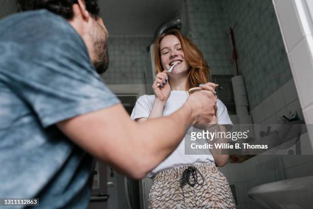 man and woman having fun while brushing their teeth - brush teeth phone stock-fotos und bilder