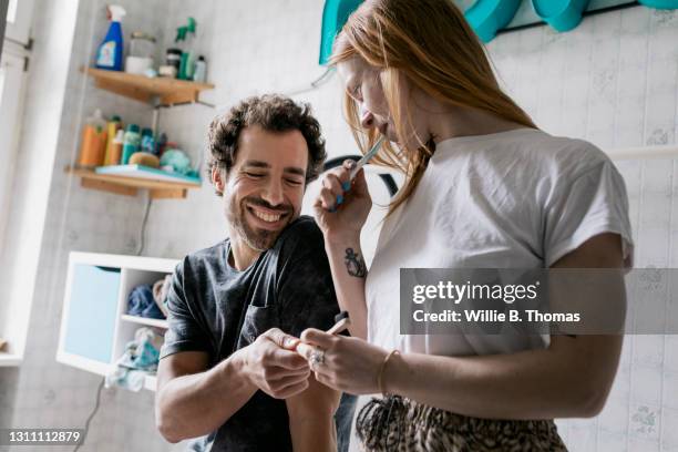 couple brushing teeth in bathroom together - toothbrush photos et images de collection