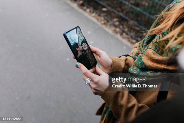 woman showing her boyfriend selfie she took on smartphone - city photos stock-fotos und bilder