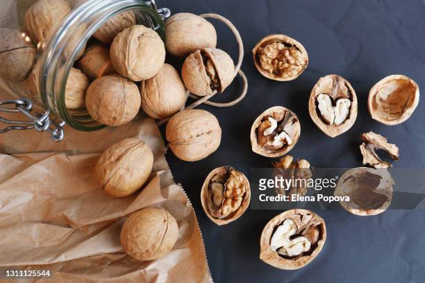 raw unpeeled and cracked walnuts on stone plate - walnut fotografías e imágenes de stock