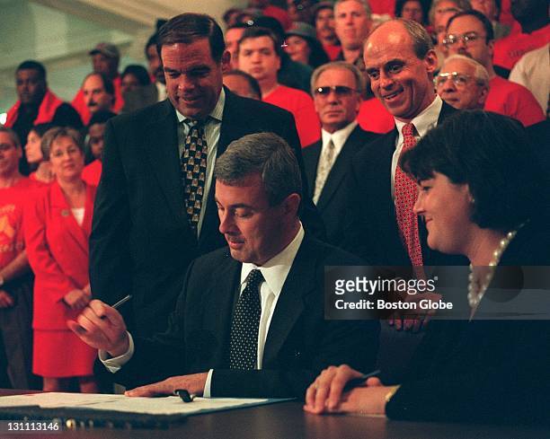 Governor Paul Cellucci signs the minimum wage bill at the Mass. State House. Steve Birbingham and Thomas Finneran look on from behind. Lt. Gov. Jane...