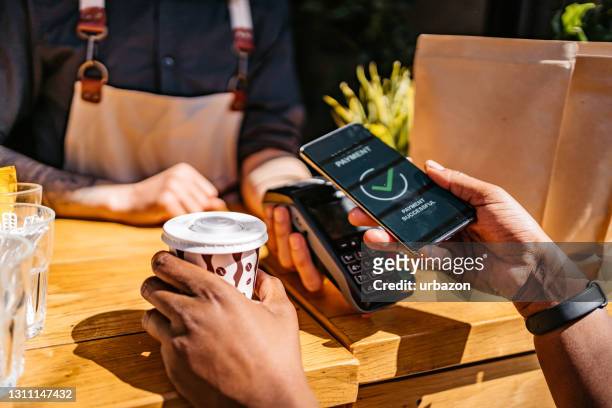 woman paying via contactless channel by mobile banking application - contactless payment stock pictures, royalty-free photos & images