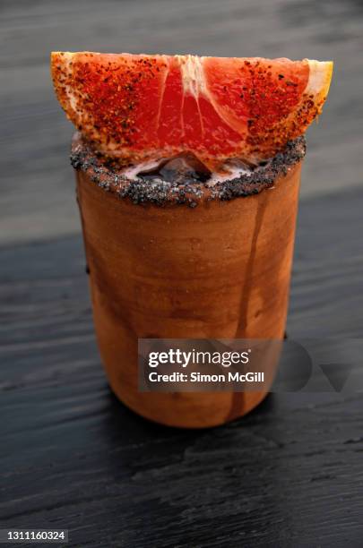 mexican tequila-based cocktail served in a clay cup on a table - tequila mexico stock-fotos und bilder