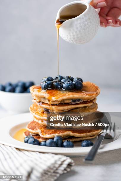 cropped hand pouring syrup on blueberry pancakes,russia - syrup drizzle stock pictures, royalty-free photos & images