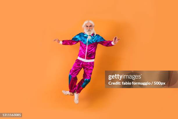 stylish senior man jumping on orange background,italy - tracksuit jacket stock-fotos und bilder