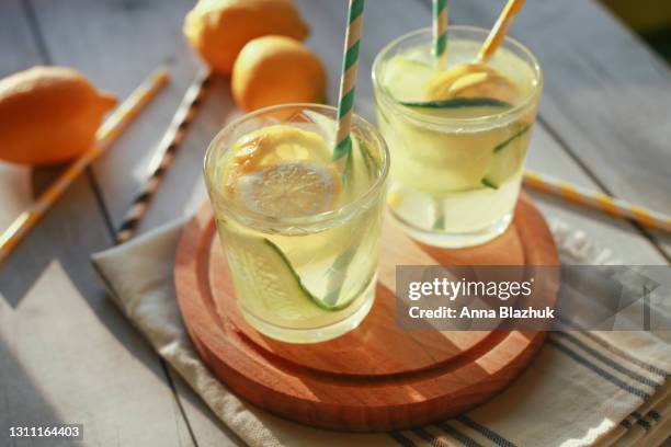 glass of homemade lemonade made of lemon and cucumber with paper drinking straws. summer cold drink for party or picnic. - lemon soda - fotografias e filmes do acervo