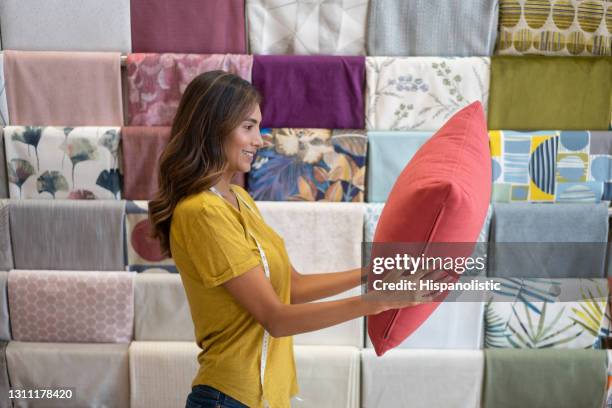 happy saleswoman working at a fabric shop and holding a cushion - woman holding throw pillow stock pictures, royalty-free photos & images