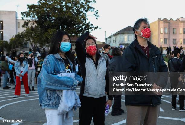 Sydney Quan and her parents, Charise Fong and Hanson Quan, watch a red lantern float in the sky following its release as hundreds gather for the...