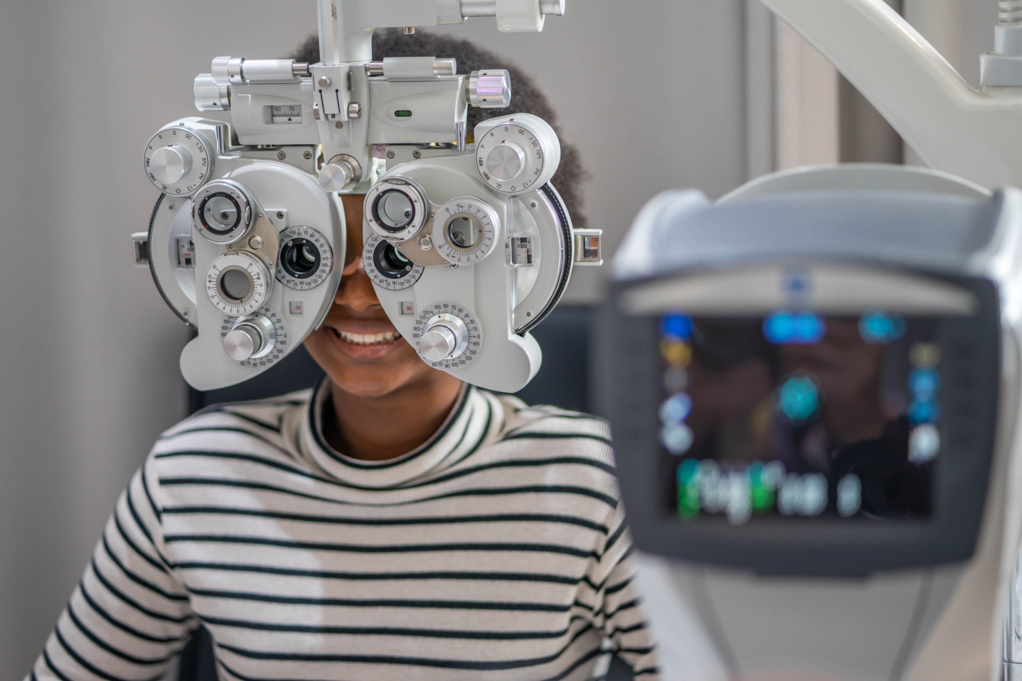 Close-up Of african teen girl Doing Eye Test On Phoropter, African teen girl checking on her eye with optometry machine. Close-up Of african teen girl Doing Eye Test On Phoropter, African teen girl checking on her eye with optometry machine.
