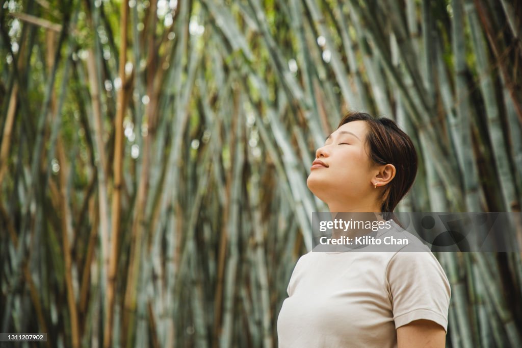 Asian woman relaxing and breathing in fresh air in a bamboo forest