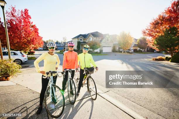 wide shot portrait of mature female friends preparing for road bike ride on fall afternoon - autumn friends coats stock pictures, royalty-free photos & images