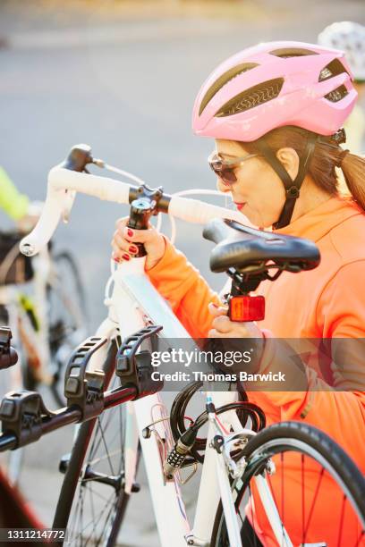 medium shot of mature woman removing road bike from rack on car before road ride on fall afternoon - taking a shot - sport imagens e fotografias de stock