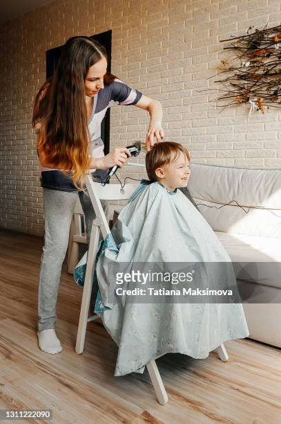 mother cutting sons hair with electric razor at home. - lockdown haircut stock pictures, royalty-free photos & images