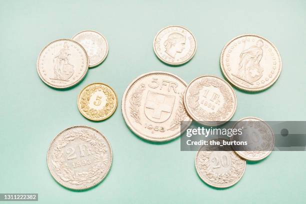 high angle view of swiss franc coins on turquoise colored background - franken stock-fotos und bilder